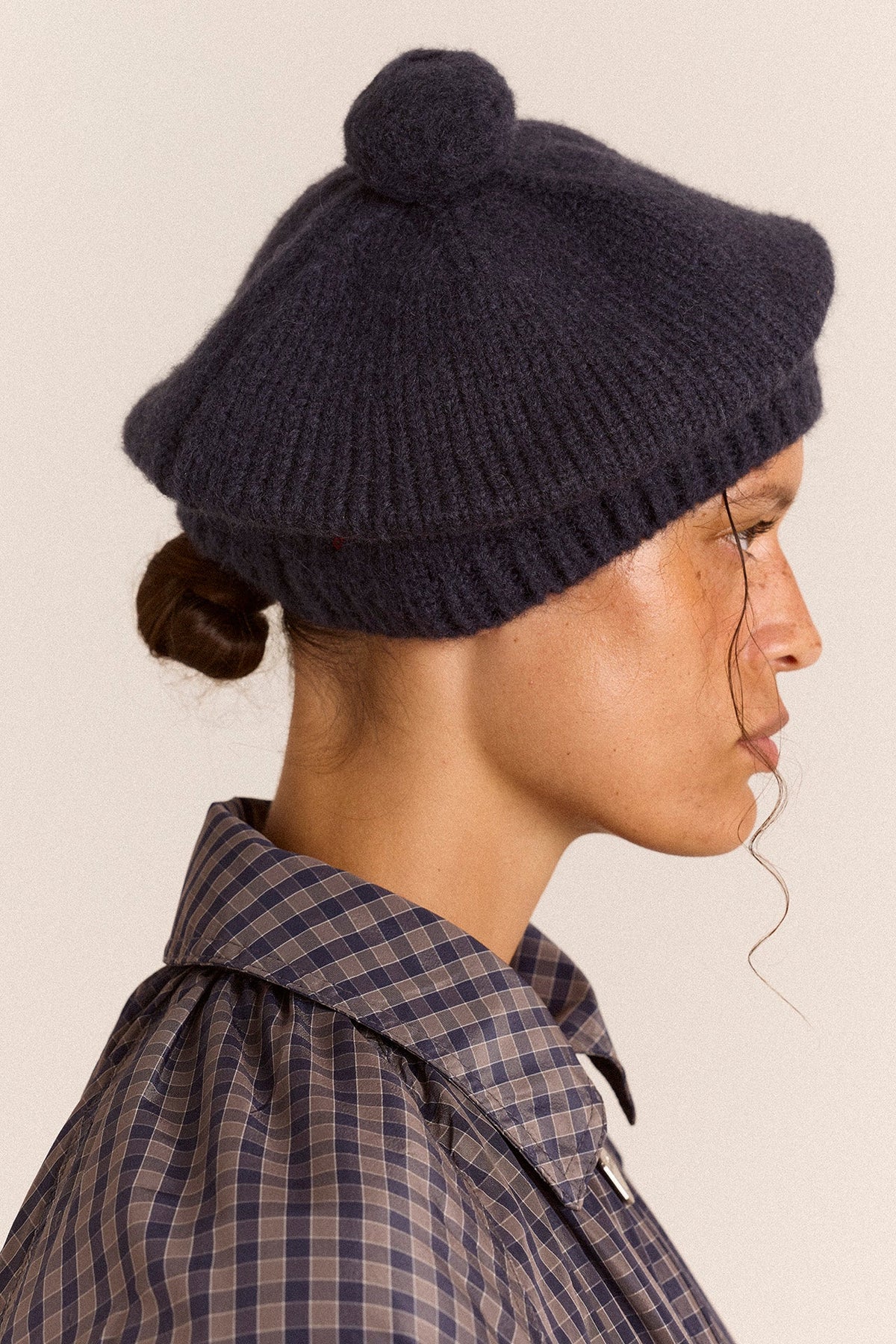 Knitted Pom Pom Beret in Navy, side view on model showing the pom pom