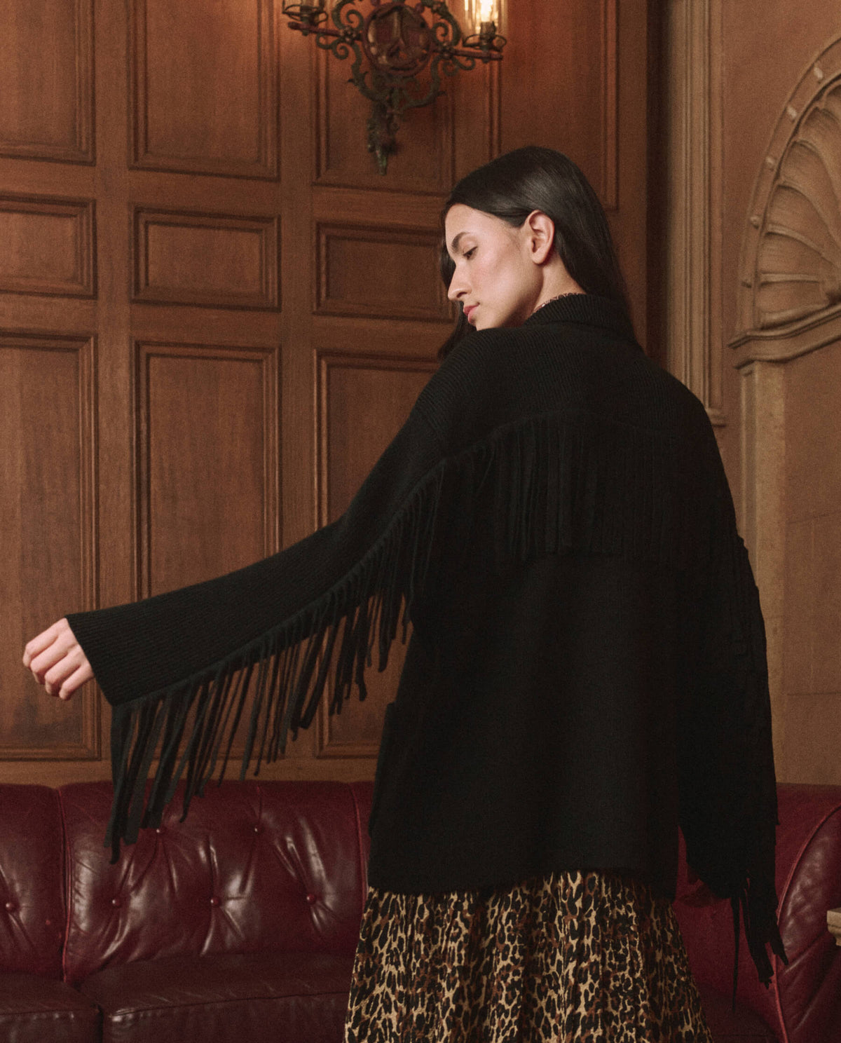 The Western Fringe Sweater Jacket in Black by The Great — back view on model showing the fringe sleeves