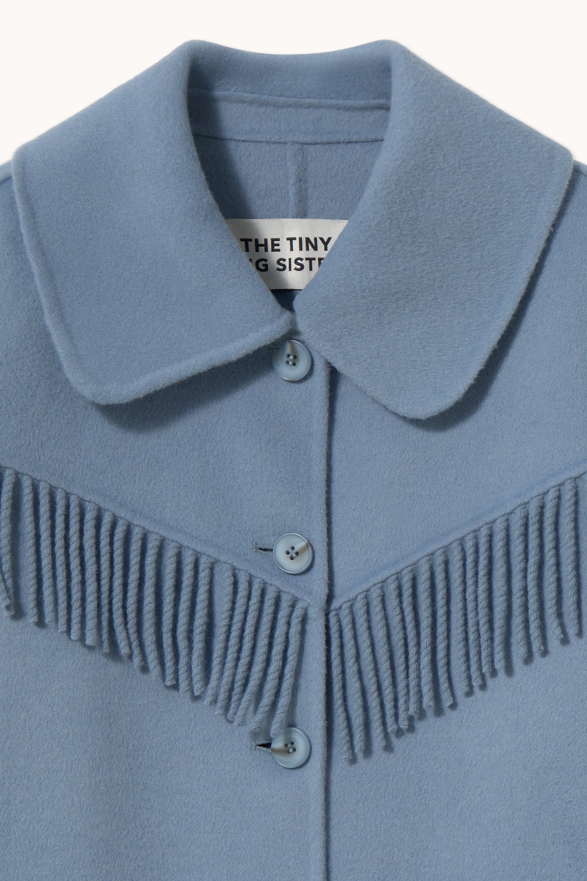 Frills Long Coat in Washed Blue by The Tiny Big Sister — close-up of the collar and fringe