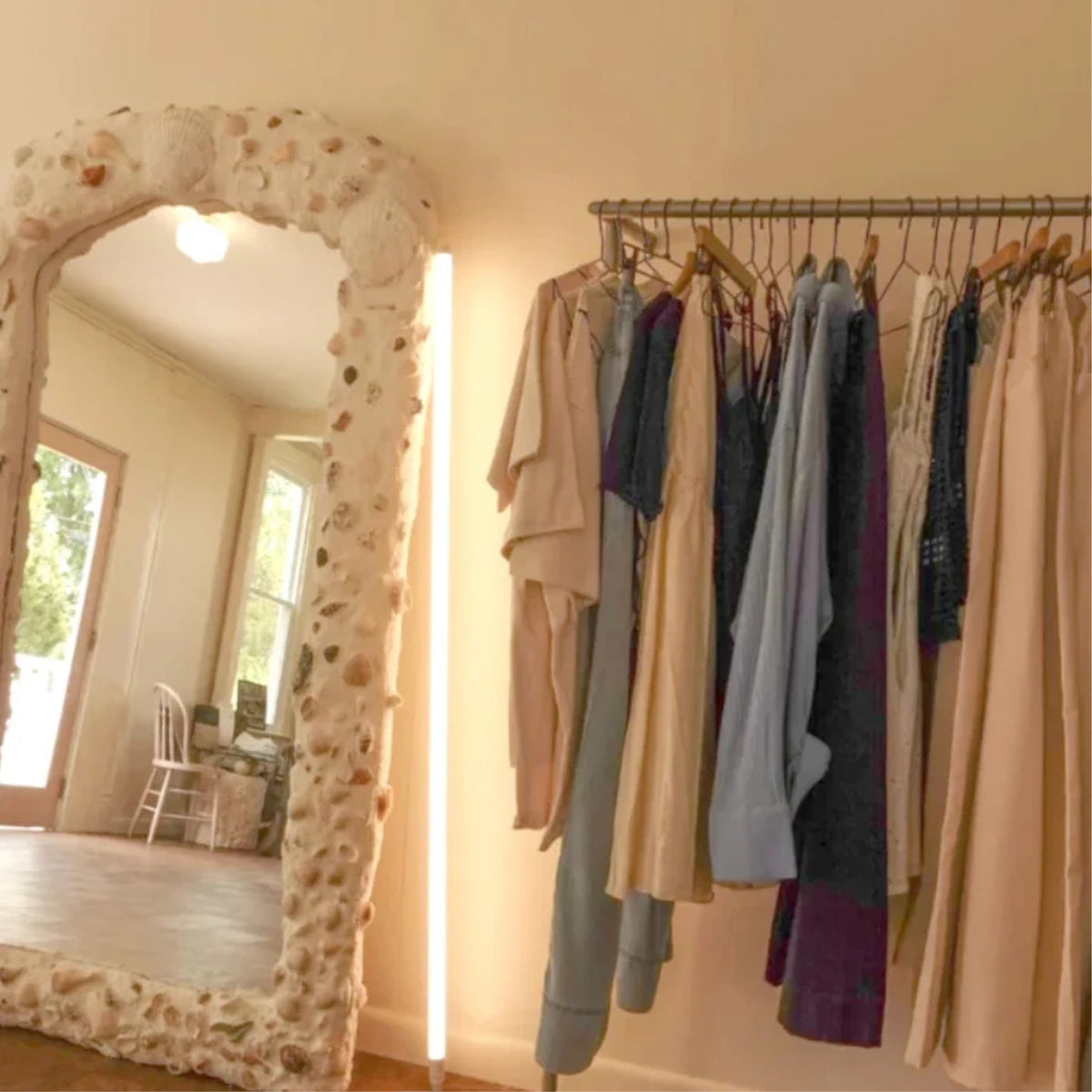 Shell mirror and a rail of neutral clothing inside Dear Neighbor Irvington