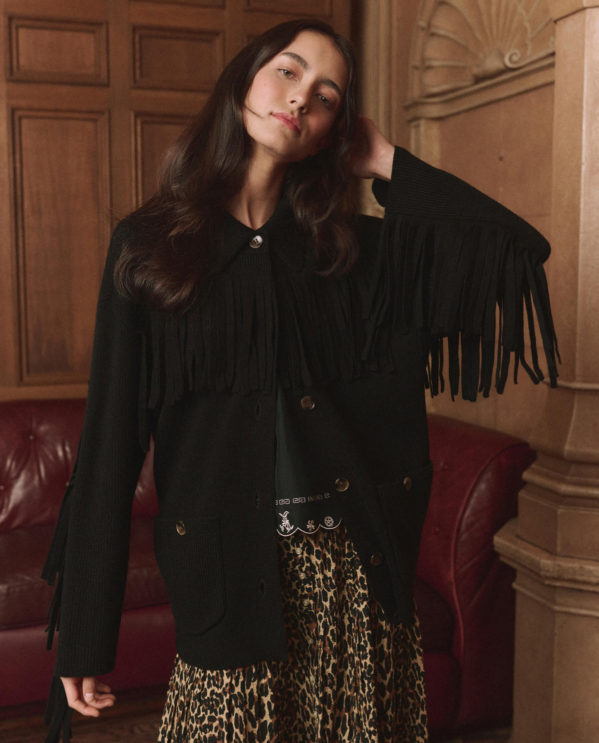 The Western Fringe Sweater Jacket in Black by The Great — front view on model styled with a leopard skirt