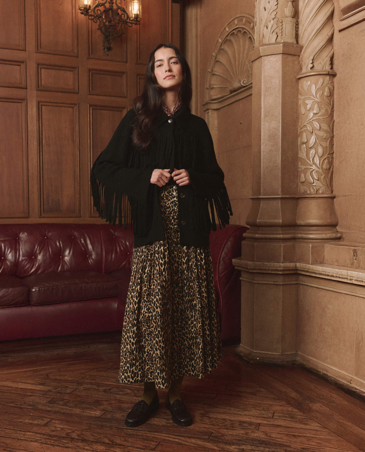 The Western Fringe Sweater Jacket in Black by The Great — full-length view styled with a leopard maxi skirt
